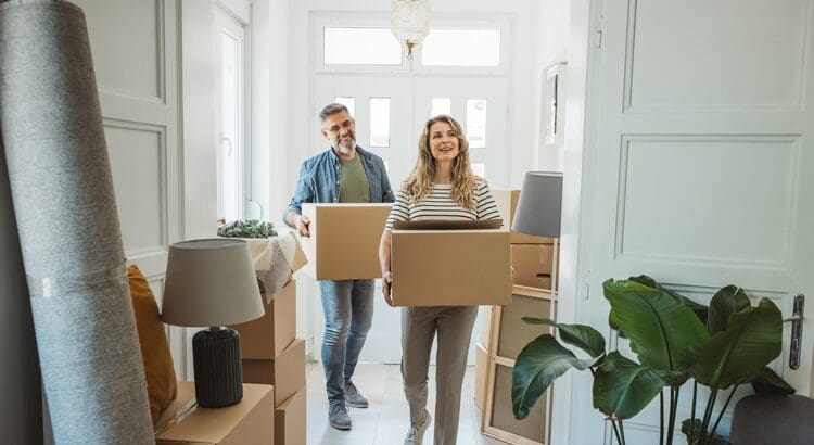 A man and woman carrying boxes in a room.