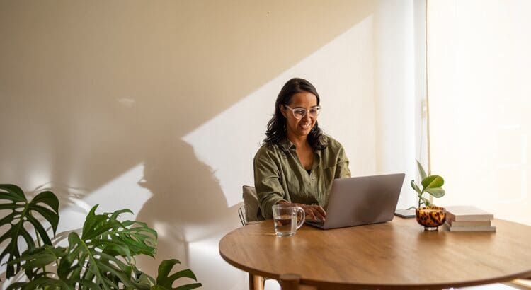 A woman sitting at a table with a laptop.