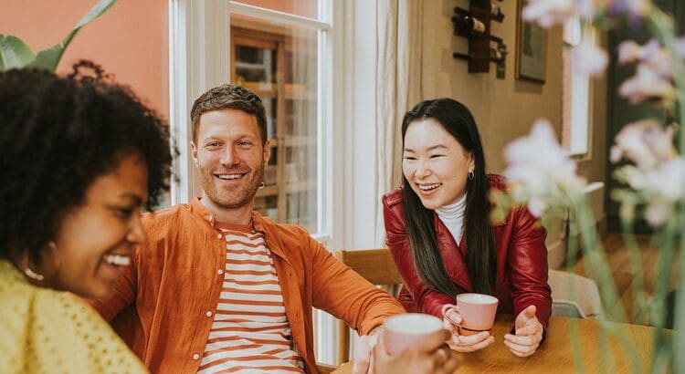 A man and woman sitting at a table with cups.