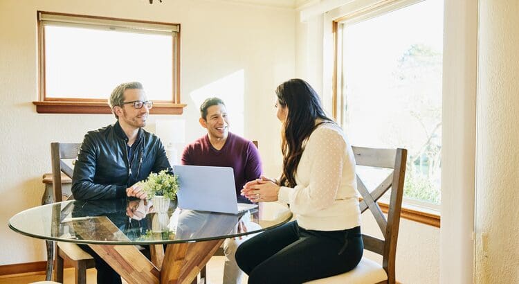Three people sitting at a table with a laptop
