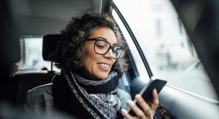 A woman in glasses and scarf looking at her phone.