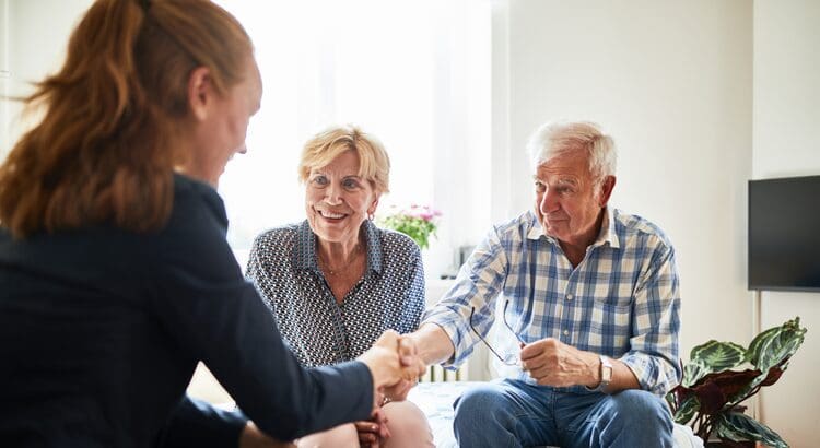 A woman shaking hands with an older man.