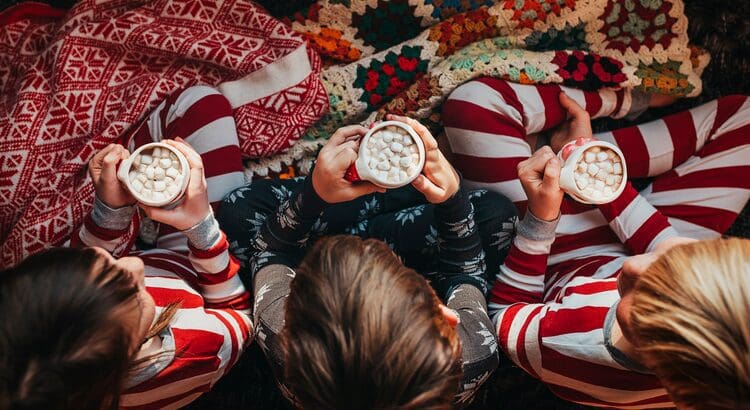 Three people in pajamas are holding cups of coffee.