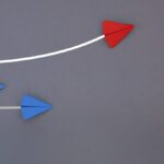 A red and blue paper airplane is flying in the air.