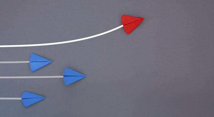 A red and blue paper airplane is flying in the air.