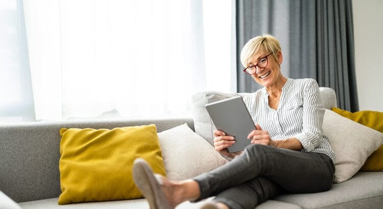 A woman sitting on the couch reading a book.