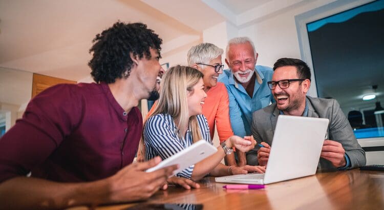 A group of people sitting around a table with a laptop.