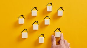 Hand arranging blocks with house icons.