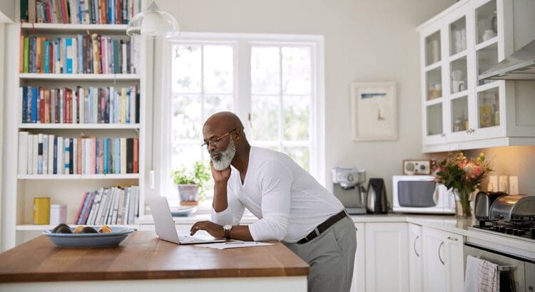 Man working on laptop in kitchen.