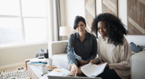 Two women working together in living room.