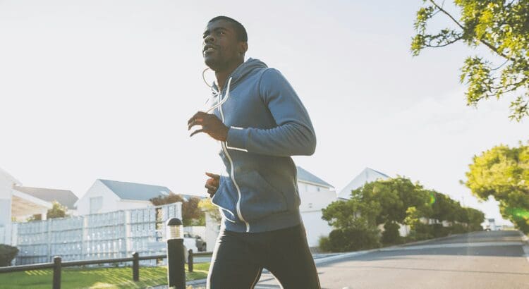 Man jogging on a sunny suburban street.