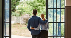 Couple embracing, looking outside through open doors.