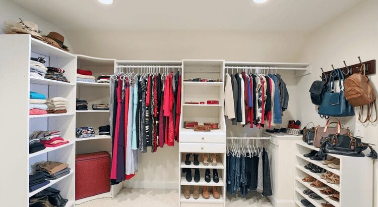 Organized walk-in closet with clothes and shoes.