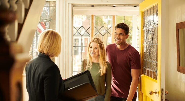 Smiling couple greeting professional at door.