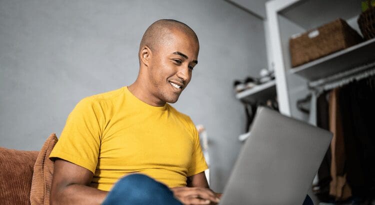 Man smiling while using a laptop.