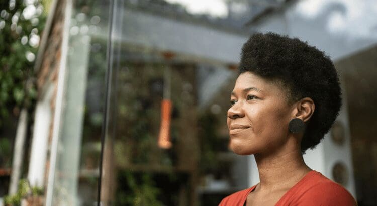Woman looking through a window, smiling thoughtfully.