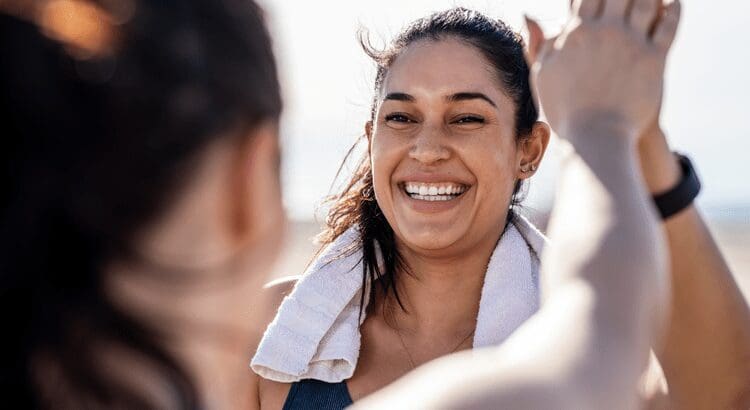 Woman smiling, giving a high-five outdoors.
