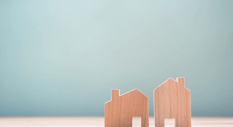 Wooden house models on light blue background.