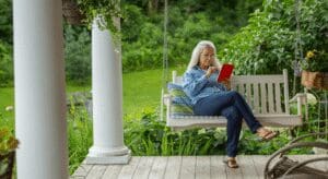 Woman reading on porch swing outside.