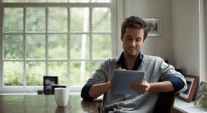 Man writing on tablet at home table.