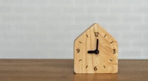 Wooden house-shaped clock on table.