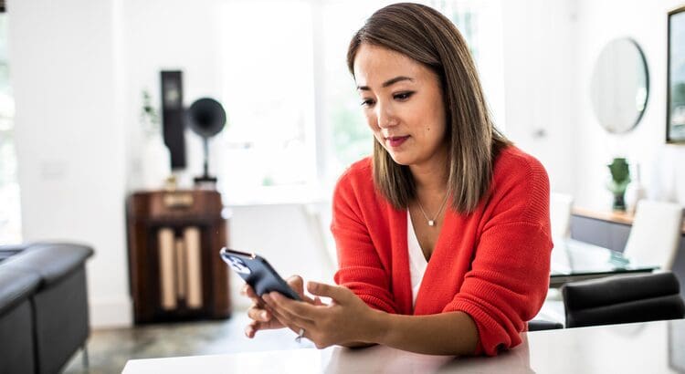 Woman in red sweater using smartphone indoors.