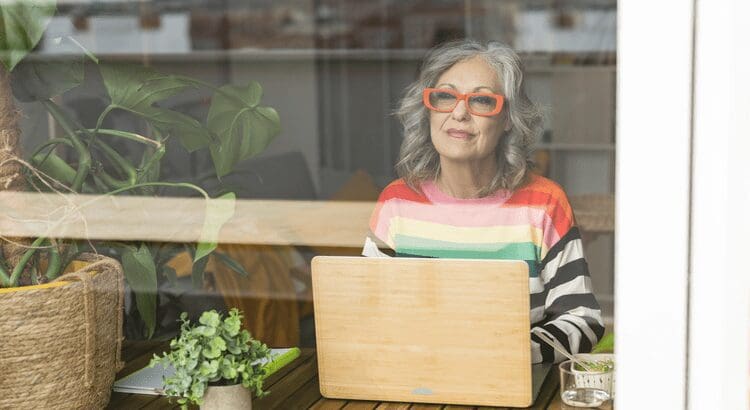 Woman with laptop, wearing colorful striped sweater.