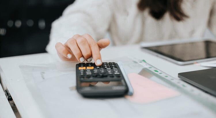 Hand using calculator on a desk.
