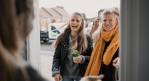 Women smiling at a doorstep with plant.