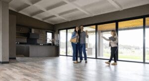 Couple touring empty modern home with realtor.