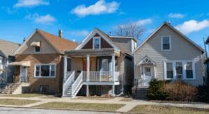 Three suburban houses under a blue sky.