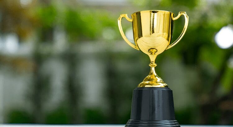 Gold trophy on a black base outdoors.