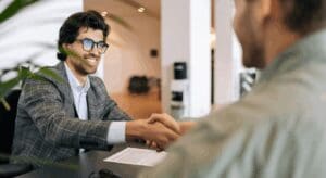 Two people shaking hands at a desk.