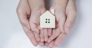 Hands holding small white house model