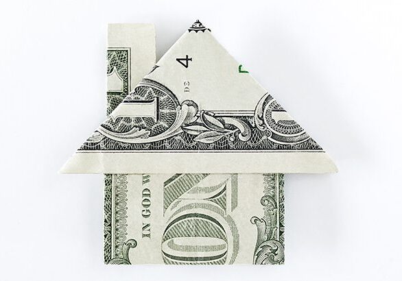 Origami dollar house on top of dollar bills on white background