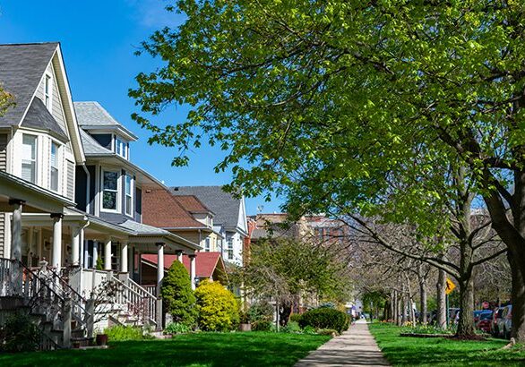 A row of old wooden homes with front lawns and a sidewalk in the North Center neighborhood of Chicago