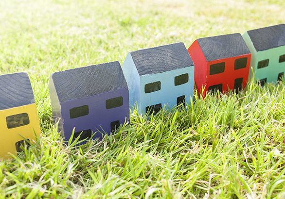 Row of wooden toy houses on grass