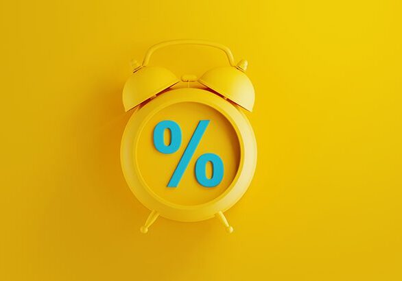 Yellow alarm clock on yellow background. There is a blue percentage sign on the clock. Reminder concept. Horizontal composition with copy space.