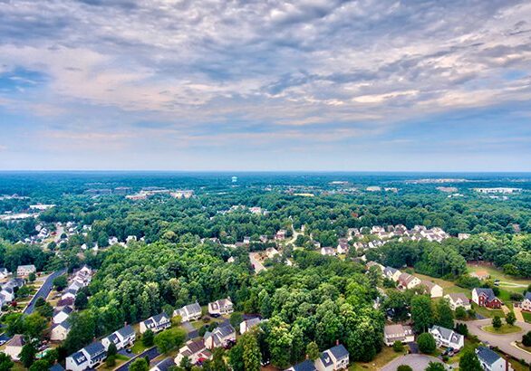 An aerial view of suburban neighborhoods from high above with the horizon and sky.