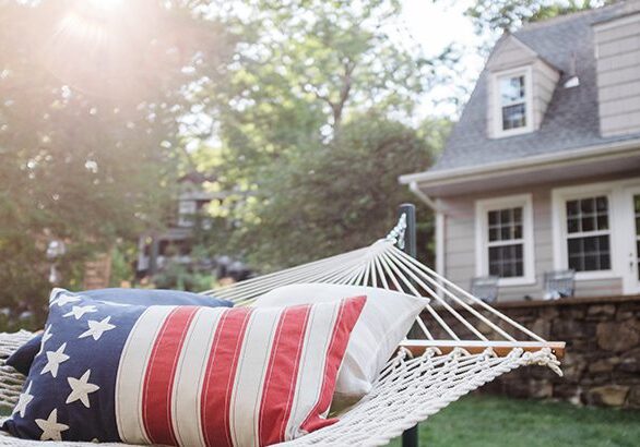 Hammock in a residential backyard with an American flag printed pillow.
