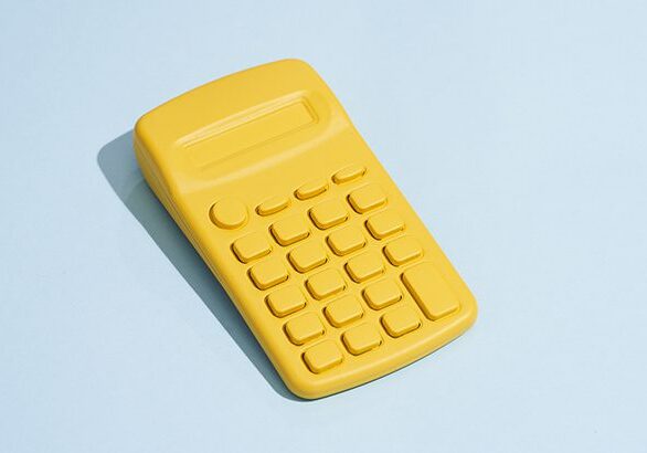 Elevated view of yellow calculator on a blue colored background