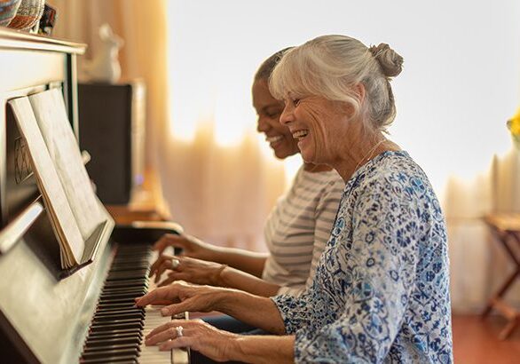 Two women playing the piano together at home