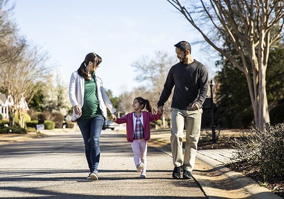 Family of three walking in suburban neighborhood
