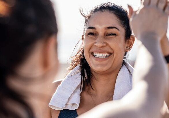 Woman smiling, giving a high-five outdoors.