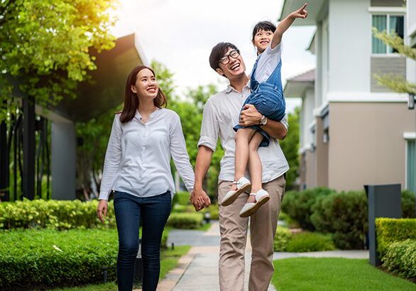 Asian family portrait daughter, mother and father walking and point to their new house in village. She looking happy with new house in modern village. Family life love relationship, or home fun leisure activity concept