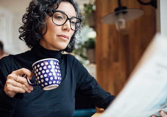 A woman sitting at a table with a cup of coffee.
