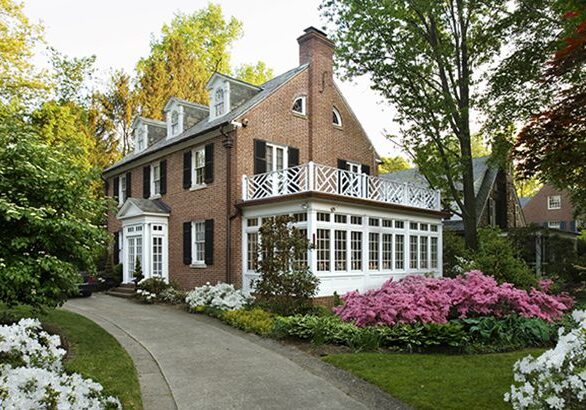 A brick house with flowers in the front yard.