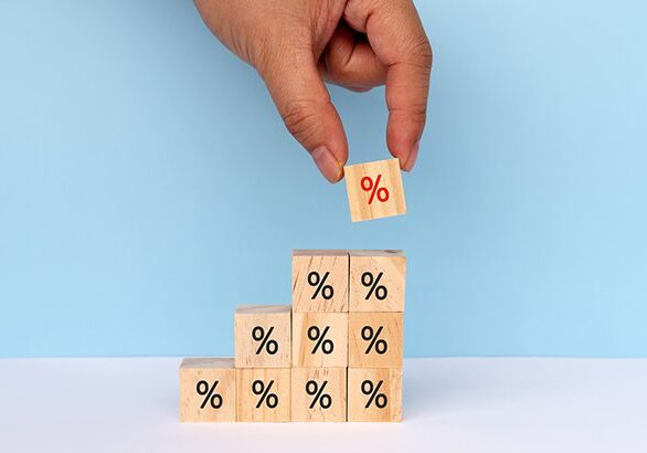 A hand holding a cube with percentages on it.