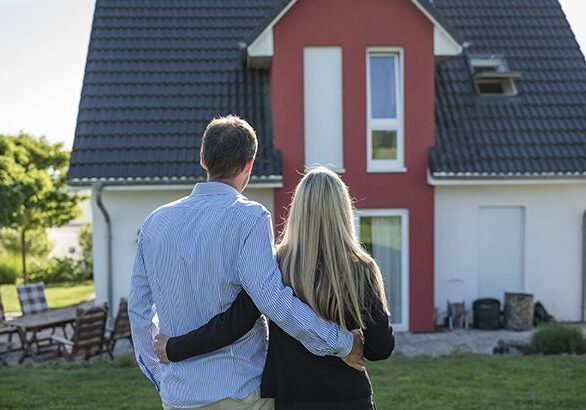 A man and woman standing in front of a house.