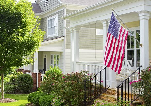 Detail of a bungalow/cottage-style front porch with an American Flag hanging from the front column.